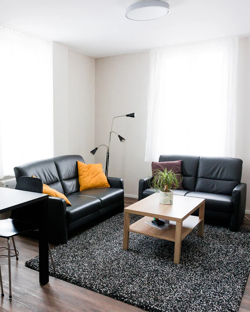 Wohnzimmer einer Wohnung mit zwei schwarzen Sofas.